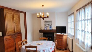 Une cuisine chaleureuse avec une table à manger, des armoires en bois, un lustre et une cheminée.