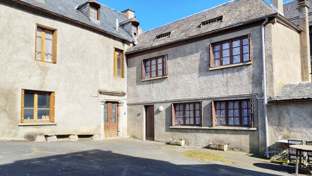 Un bâtiment traditionnel en pierre, doté de nombreuses fenêtres et d’une entrée centrale.