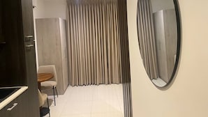 A modern bedroom with a large wardrobe, a round mirror, and a chair. - Unique Abodes (Accra)
