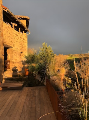 A rustic stone building with a wooden deck leading to a stone entrance. - Cottage "Le Pentadou – Le Patio" with Shared Pool, Private Terrace, and Wi-Fi (Felzins)