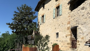A stone building with a wooden deck, a stone wall, and a tree.