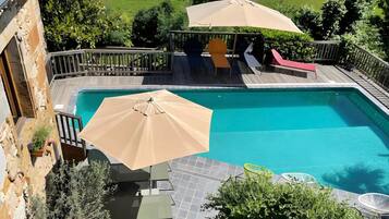 Una piscina con pérgola, mobiliario exterior y plantas en macetas.