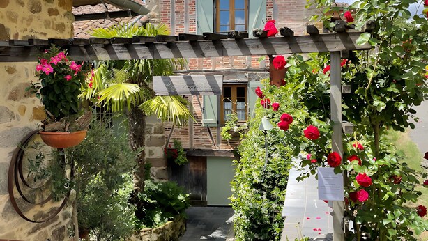 A rustic building with a stone facade, a wooden gate, and a garden with red flowers. - Cachou Guest Room with Shared Pool, Private Terrace and Wi-Fi (Felzins)