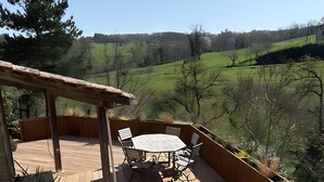A wooden deck with a table and chairs, surrounded by planters and a pergola. - Cachou Guest Room with Shared Pool, Private Terrace and Wi-Fi (Felzins)