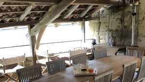 A wooden deck with a table and chairs, a hanging light fixture, and a view of the sea. - Cachou Guest Room with Shared Pool, Private Terrace and Wi-Fi (Felzins)