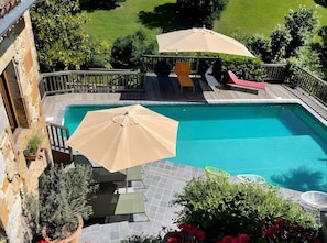 Una piscina con pérgola, mobiliario exterior y plantas en macetas.