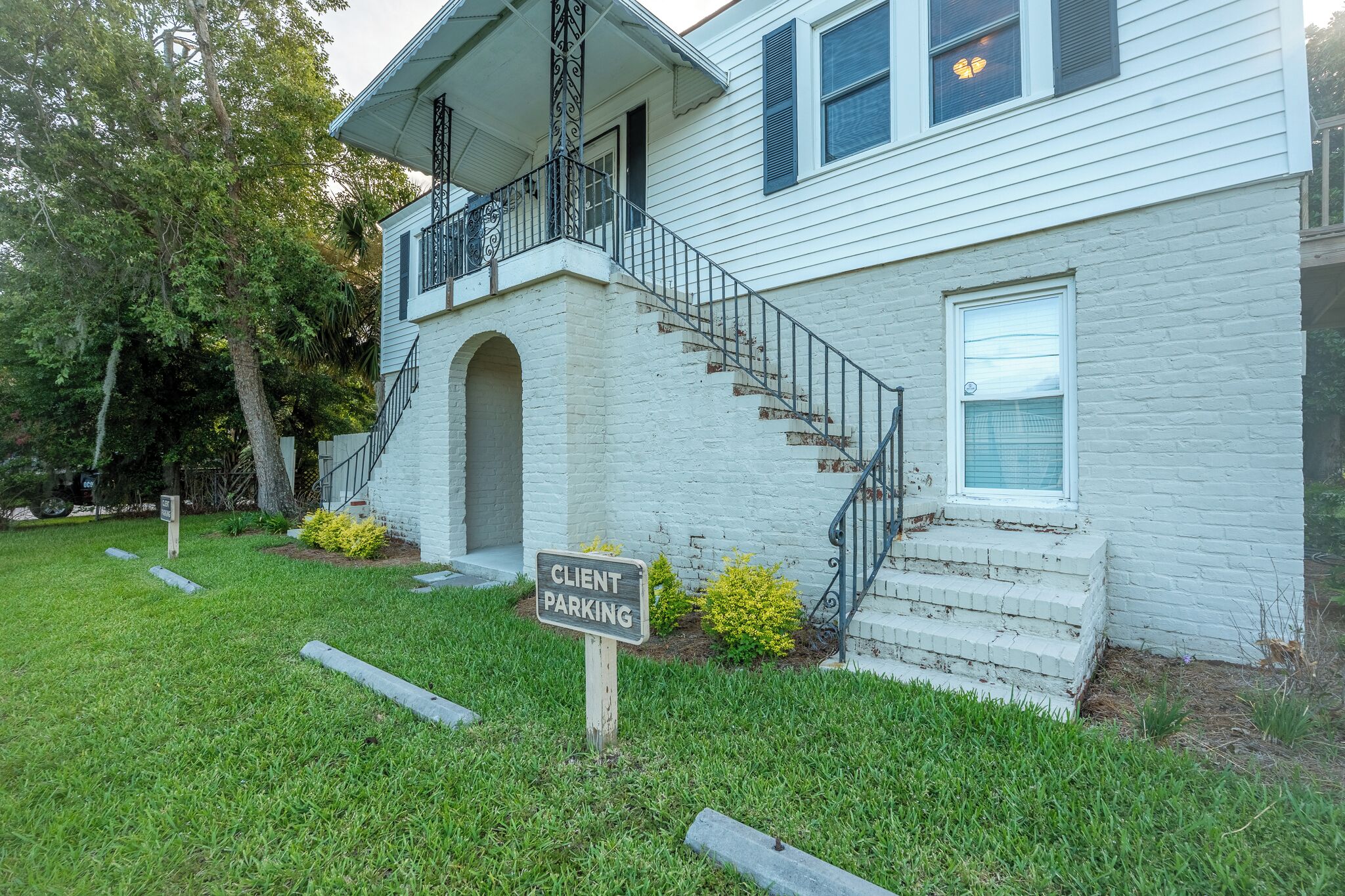 A two-story house with a front porch, a staircase, and a 'Client Parking' sign.