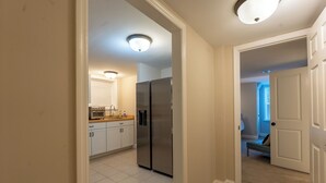 Una cocina con armarios blancos, un refrigerador de acero inoxidable y una encimera con lavamanos y estufa.