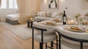 Una sala moderna con un sofá, una mesa de comedor dispuesta para una comida, y un cuadro abstracto grande en la pared.