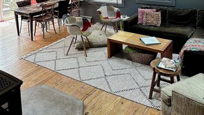 Tilava olohuone, jossa on korkea katto, suuret ikkunat ja moderni kattotuuletin.