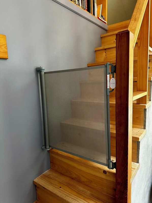 Un escalier en bois surmonté d’une barrière de sécurité en métal.