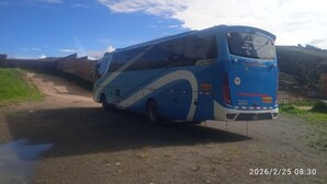 Een blauwe bus geparkeerd op een onverharde weg, met een heldere lucht op de achtergrond.