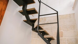 A spiral staircase with wooden steps and black metal railings against a stone wall. - [La Portulaca] Cozy Apt. in Molfetta (Molfetta)