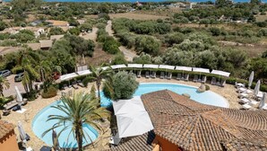 Un resort con una amplia piscina, sillas de descanso y vista al mar.