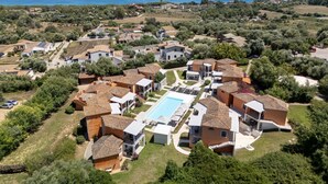 Vista aérea de una zona residencial con casas, piscina y vistas al mar.