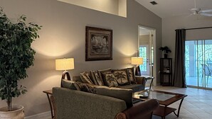 A spacious living room with a large couch, a coffee table, and a potted plant.