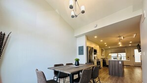 A modern kitchen with a central island, stainless steel appliances, and a dining area with a wooden table and chairs. - Skyridge Resort -Near Banff Entrance (Harvie Heights)