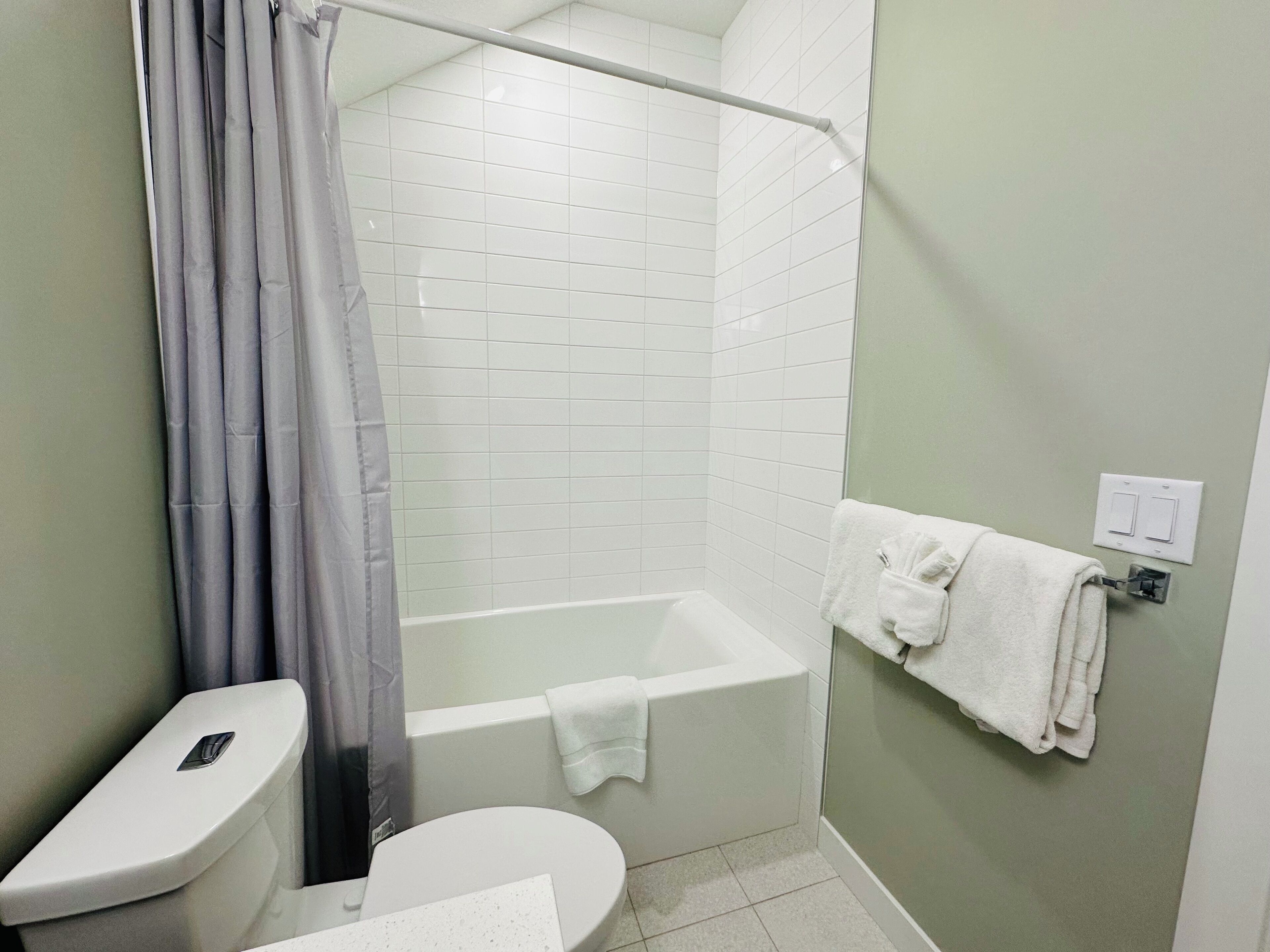 Une salle de bain équipée de toilettes, d’une baignoire et d’un rideau de douche.
