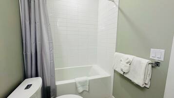 Une salle de bain équipée de toilettes, d’une baignoire et d’un rideau de douche.