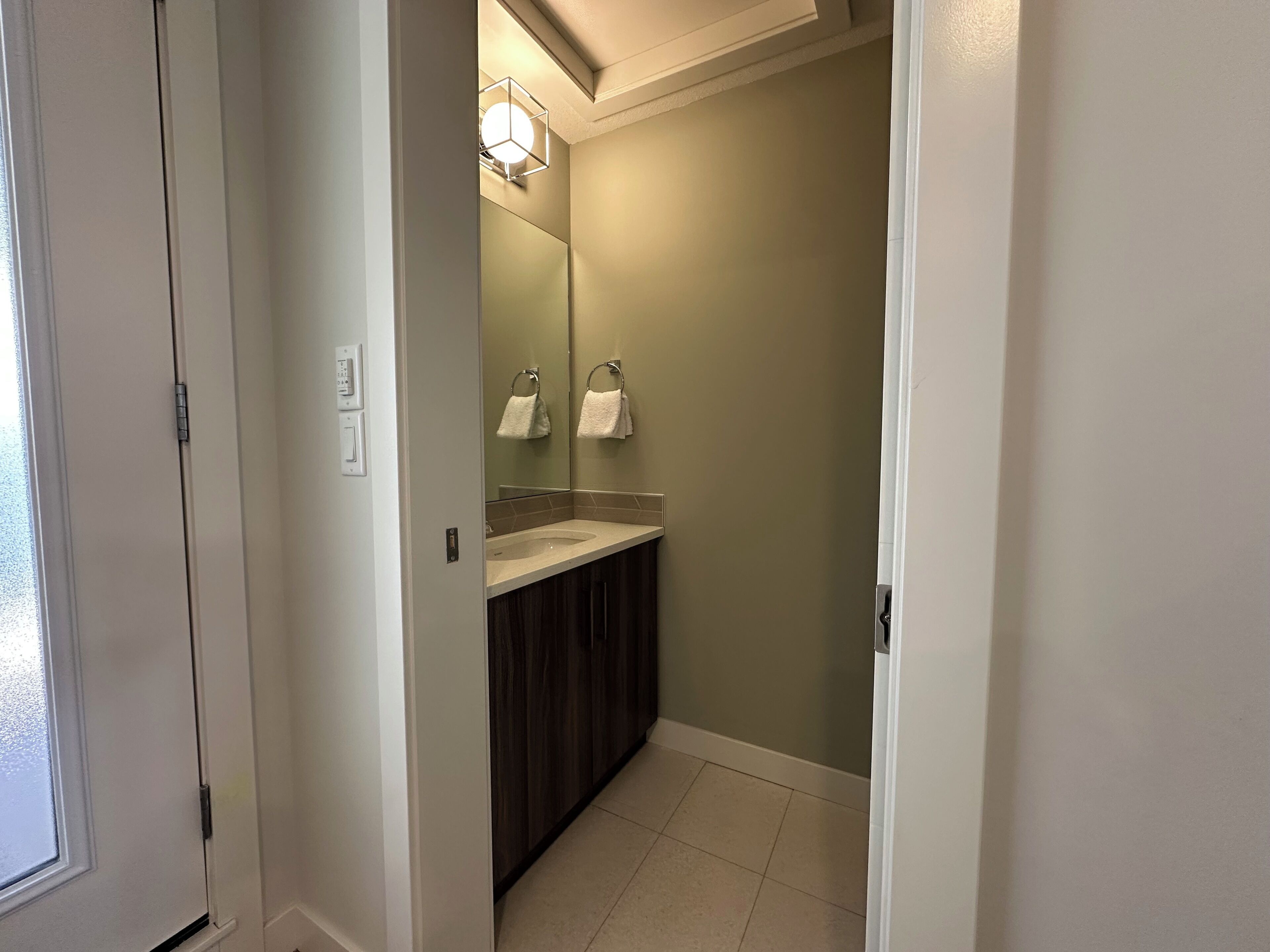 Une salle de bain équipée d’un lavabo, d’un miroir, d’un porte-serviettes et d’un luminaire.