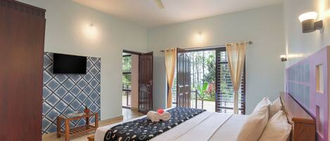 A bedroom with a bed, a ceiling fan, a TV mounted on the wall, and a window with curtains.