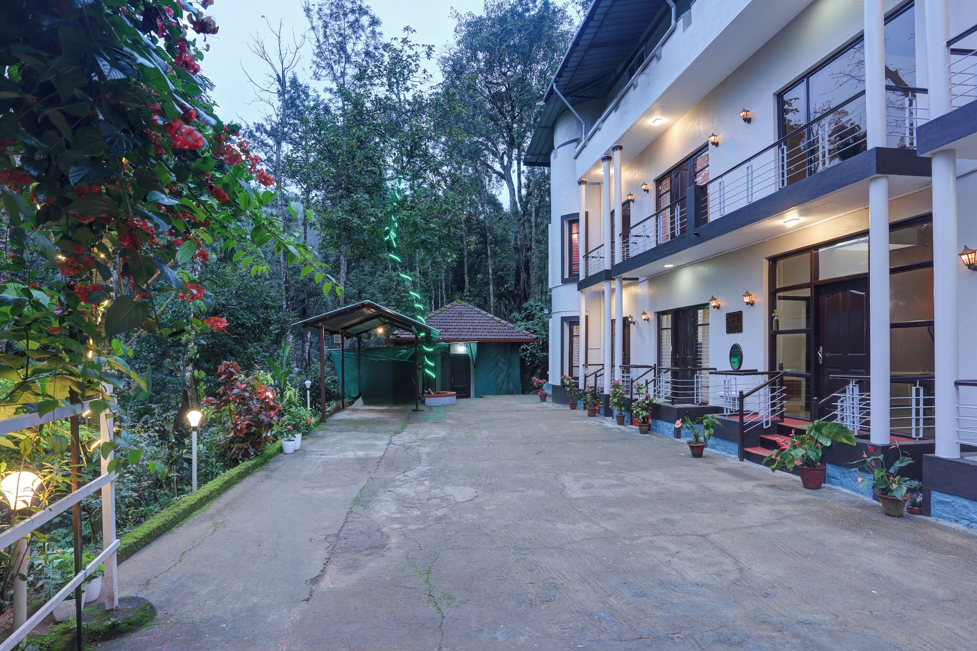 A two-story building with a covered outdoor area, potted plants, and a pathway leading to the entrance.
