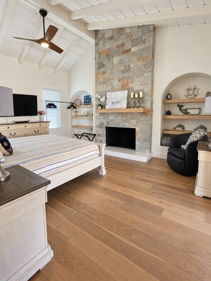 A bedroom with a bed, a TV, a fireplace, and a ceiling fan. - Stunning 4BR/3BA Home in Sunset Cliffs – Walk to Ocean (San Diego)