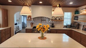 A modern kitchen with a large island, pendant lighting, and a backsplash. - Stunning 4BR/3BA Home in Sunset Cliffs – Walk to Ocean (San Diego)