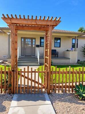 A wooden pergola entrance to a house with a gated driveway, a front door, and a bench outside. - Stunning 4BR/3BA Home in Sunset Cliffs – Walk to Ocean (San Diego)