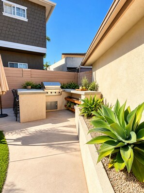 A modern outdoor patio with a barbecue grill, seating area, and planters. - Stunning 4BR/3BA Home in Sunset Cliffs – Walk to Ocean (San Diego)