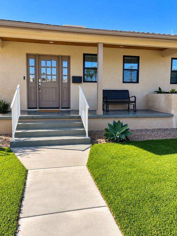 A building with a front entrance, a bench, and a well-maintained lawn. - Stunning 4BR/3BA Home in Sunset Cliffs – Walk to Ocean (San Diego)