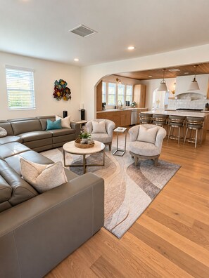 A modern living room with a sectional sofa, a round coffee table, and two armchairs. - Stunning 4BR/3BA Home in Sunset Cliffs – Walk to Ocean (San Diego)