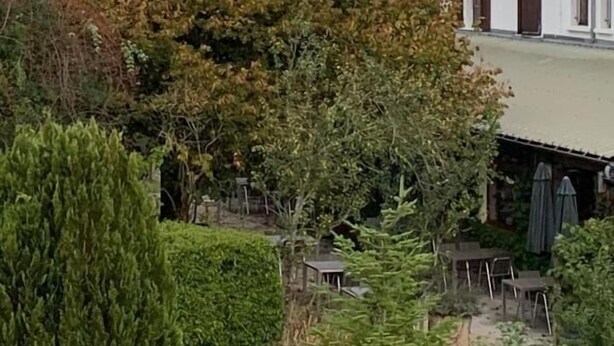 A house with a tiled roof, a small patio with a table and chairs, and a view of mountains in the background. - Au Sans Souci (Saint-Paul-lès-Monestier)