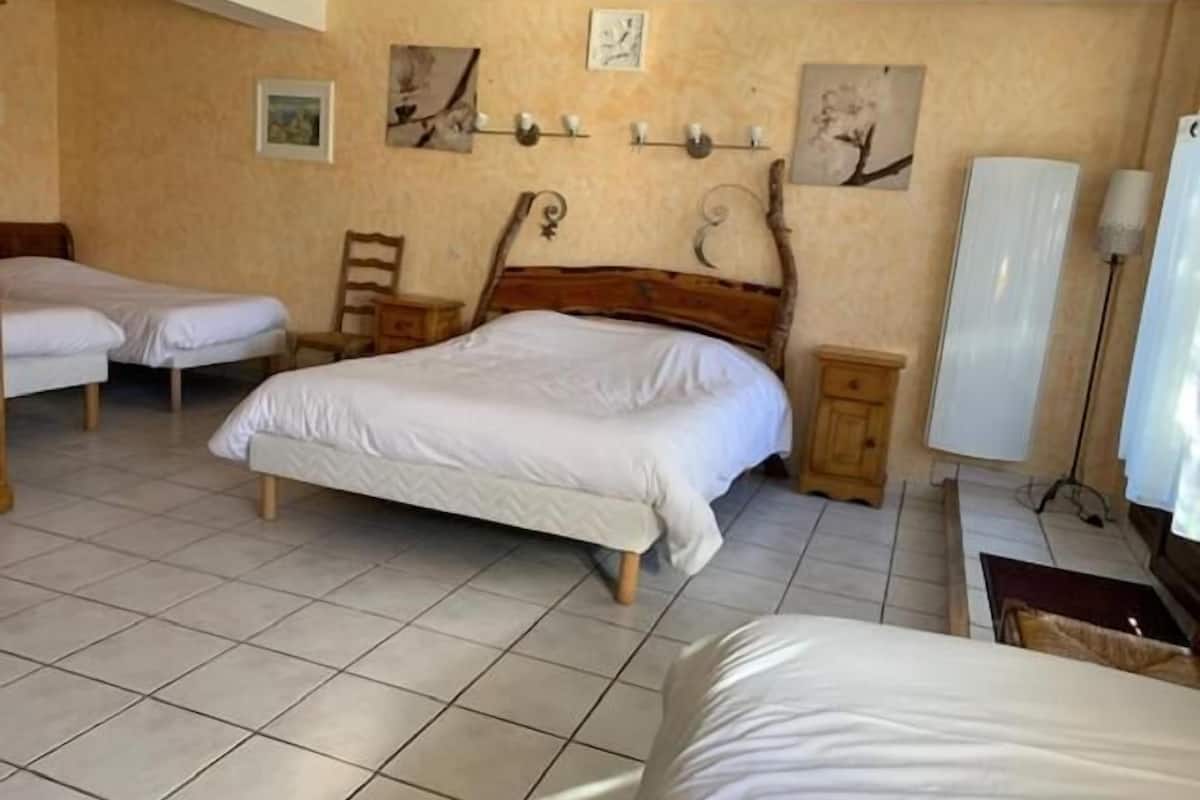 Een slaapkamer met twee eenpersoonsbedden, een houten hoofdbord, een nachtkastje en wandplanken met decoratieve objecten.