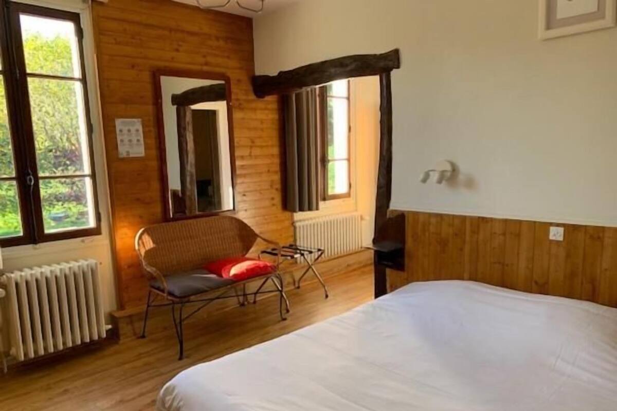 Een kamer met een bed, een stoel, een radiator en een raam.