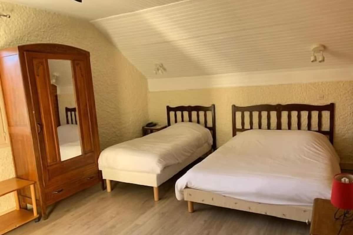 Een slaapkamer met twee eenpersoonsbedden, een houten garderobe, een klein nachtkastje en een rode lamp.