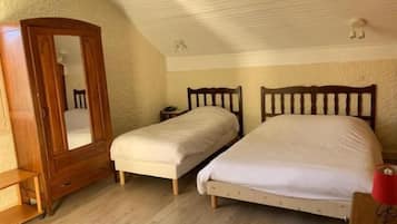Une chambre avec deux lits simples, une armoire en bois, une petite table de chevet et une lampe rouge.