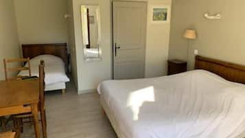 Een slaapkamer met een enkel bed, een houten stoel, een bureau, een spiegel en een deur.