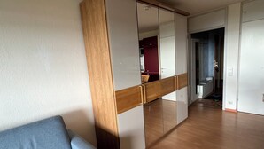 A modern room with a wooden wardrobe, a grey sofa, and a hallway leading to a bathroom. - Northern Black Forest vacation app. 44 sqm, Dieter Hoffmann Freudenstadt-Kniebis. (Freudenstadt)