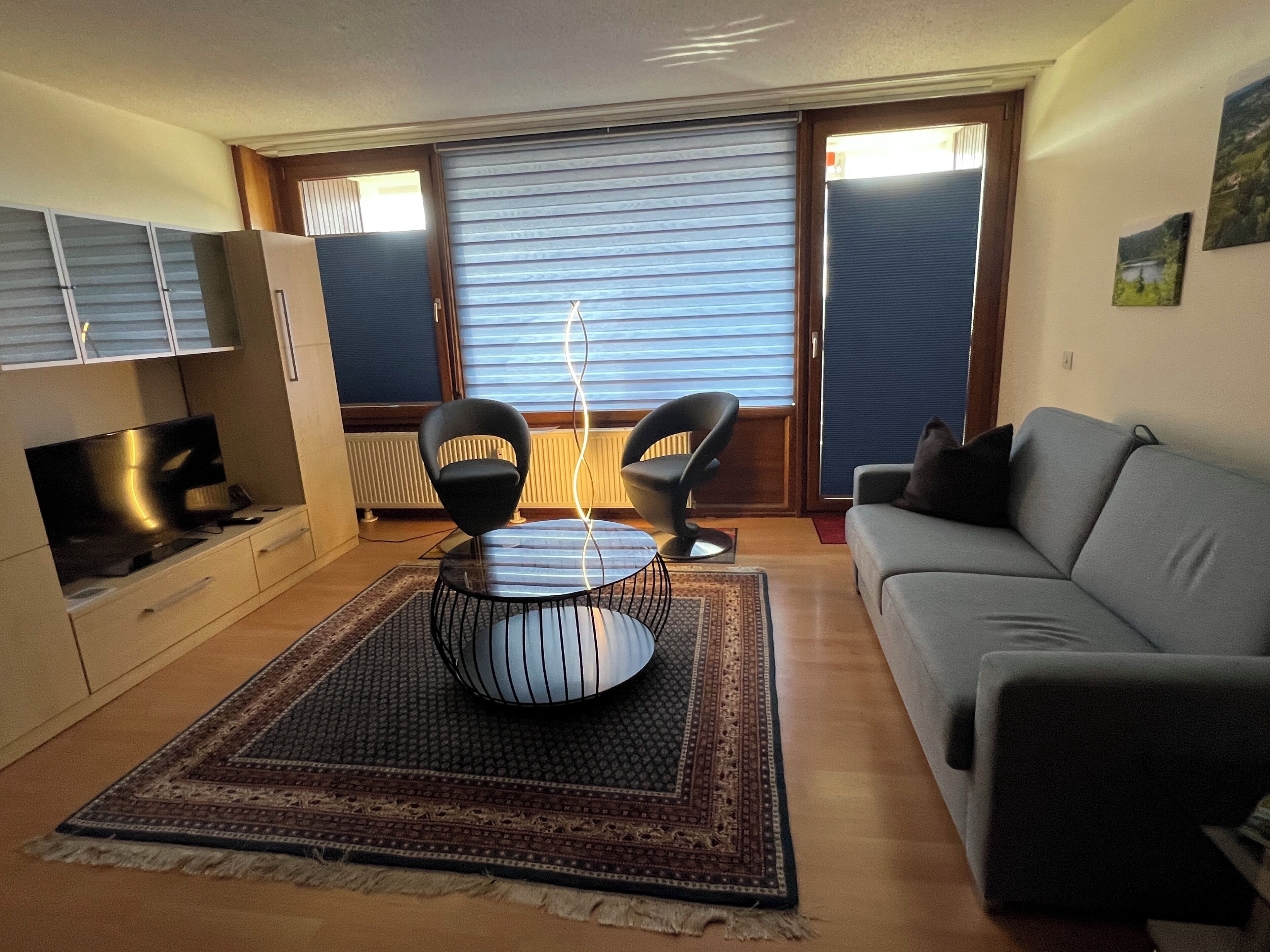 A living room with a sofa, a TV, a coffee table, and a patterned rug.
