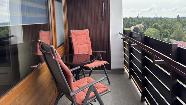 A balcony with two chairs, a table, and a view of a forested area. - Northern Black Forest vacation app. 44 sqm, Dieter Hoffmann Freudenstadt-Kniebis. (Freudenstadt)