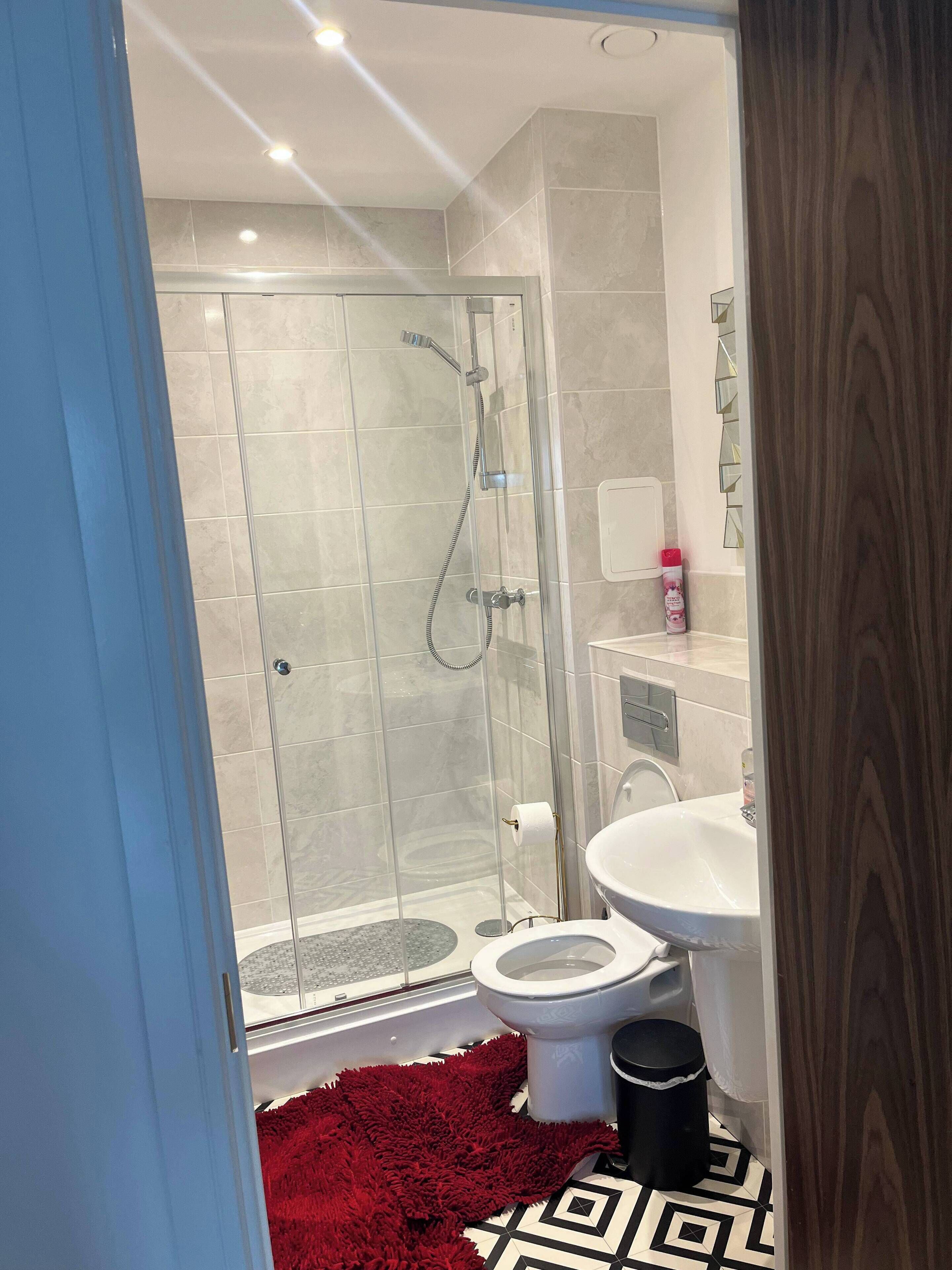 A modern bathroom with a glass-enclosed shower, a white toilet, and a sink.