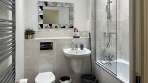 Een moderne badkamer met een glazen douchecabine, een wastafel op voet en een toilet.