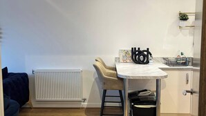 Een moderne keuken met een eethoek, met een witte radiator, een tafel met stoelen en een hanglamp.