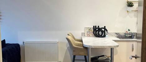 Una cucina moderna con zona pranzo, caratterizzata da un termosifone bianco, un tavolo con sedie e un lampadario.