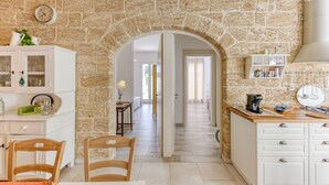 A kitchen with stone walls, a wooden dining table, chairs, a white cabinet, and a coffee machine. - Fantastic pool villa w/ private park 2km from sea (Castro)