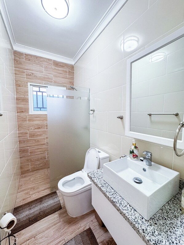 A bathroom with a toilet, sink, and shower area.