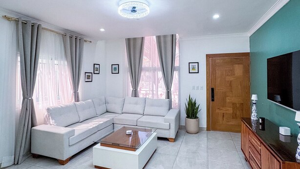Una sala de estar moderna con un sofá modular, una mesa de centro, un televisor y un mueble de madera.