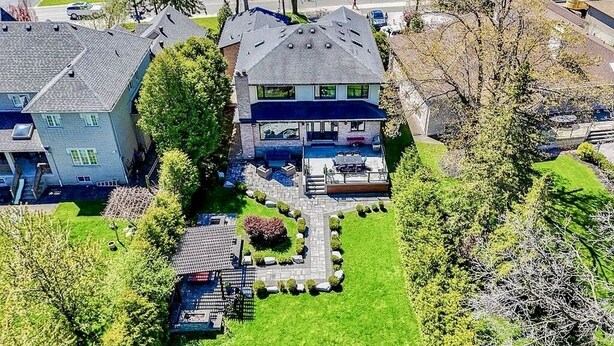 Une maison à deux étages avec un grand jardin à l’avant, une terrasse et une piscine.