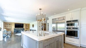 Une cuisine moderne avec des meubles blancs, un grand îlot central et des appareils électroménagers intégrés.